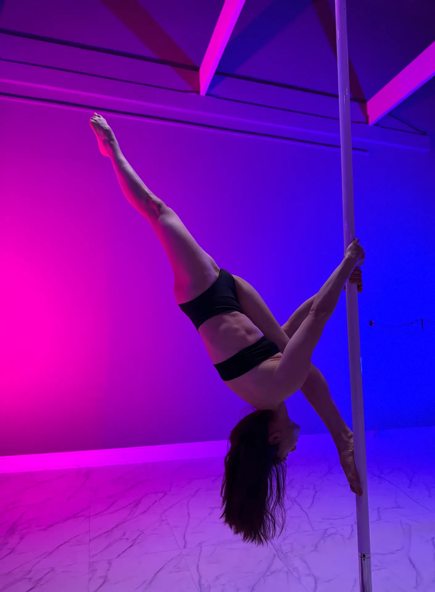 Ira inverted on the pole under studio lighting